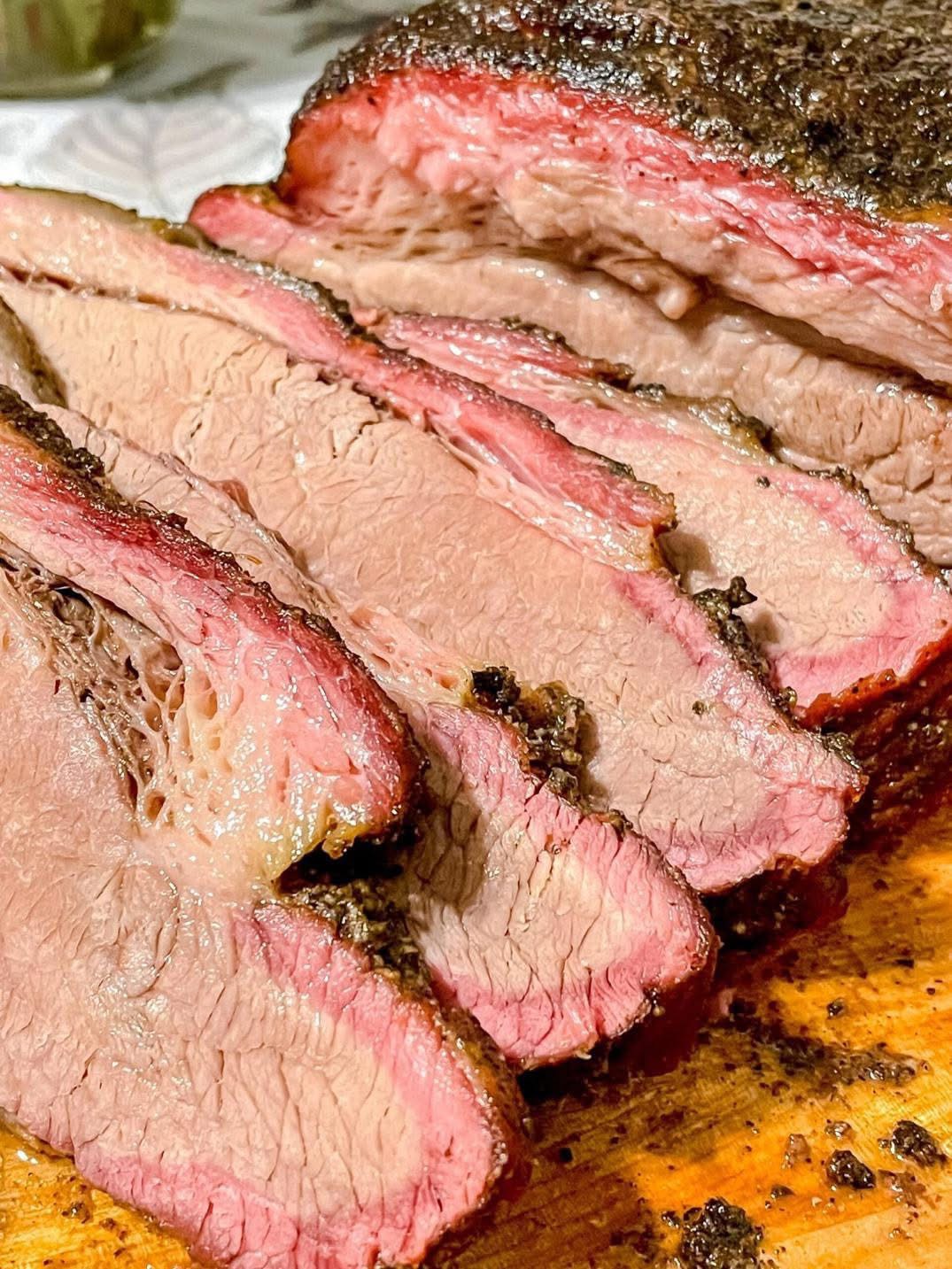 Sliced brisket with a smoky crust and pink interior on a cutting board
