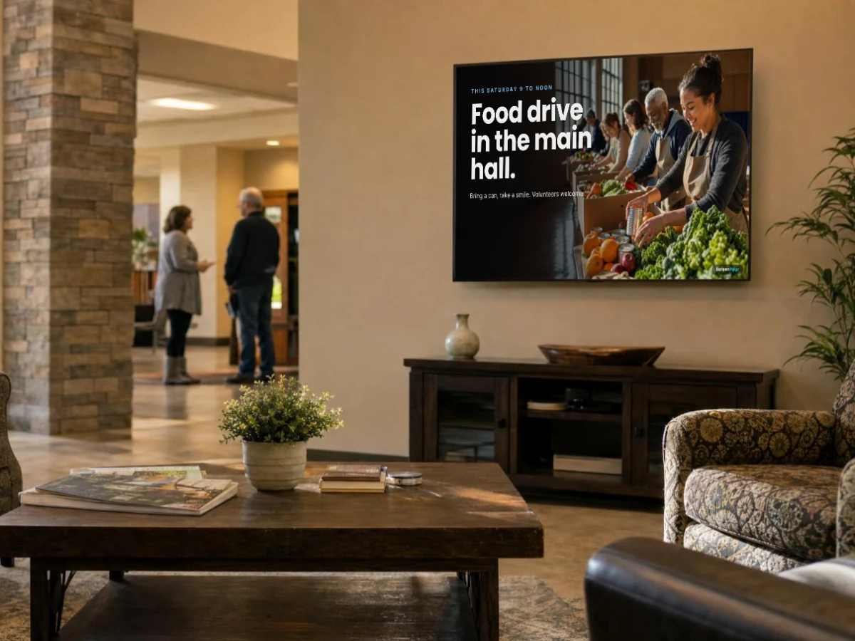 A screen in a community center lobby announcing a Saturday food drive with volunteers sorting food