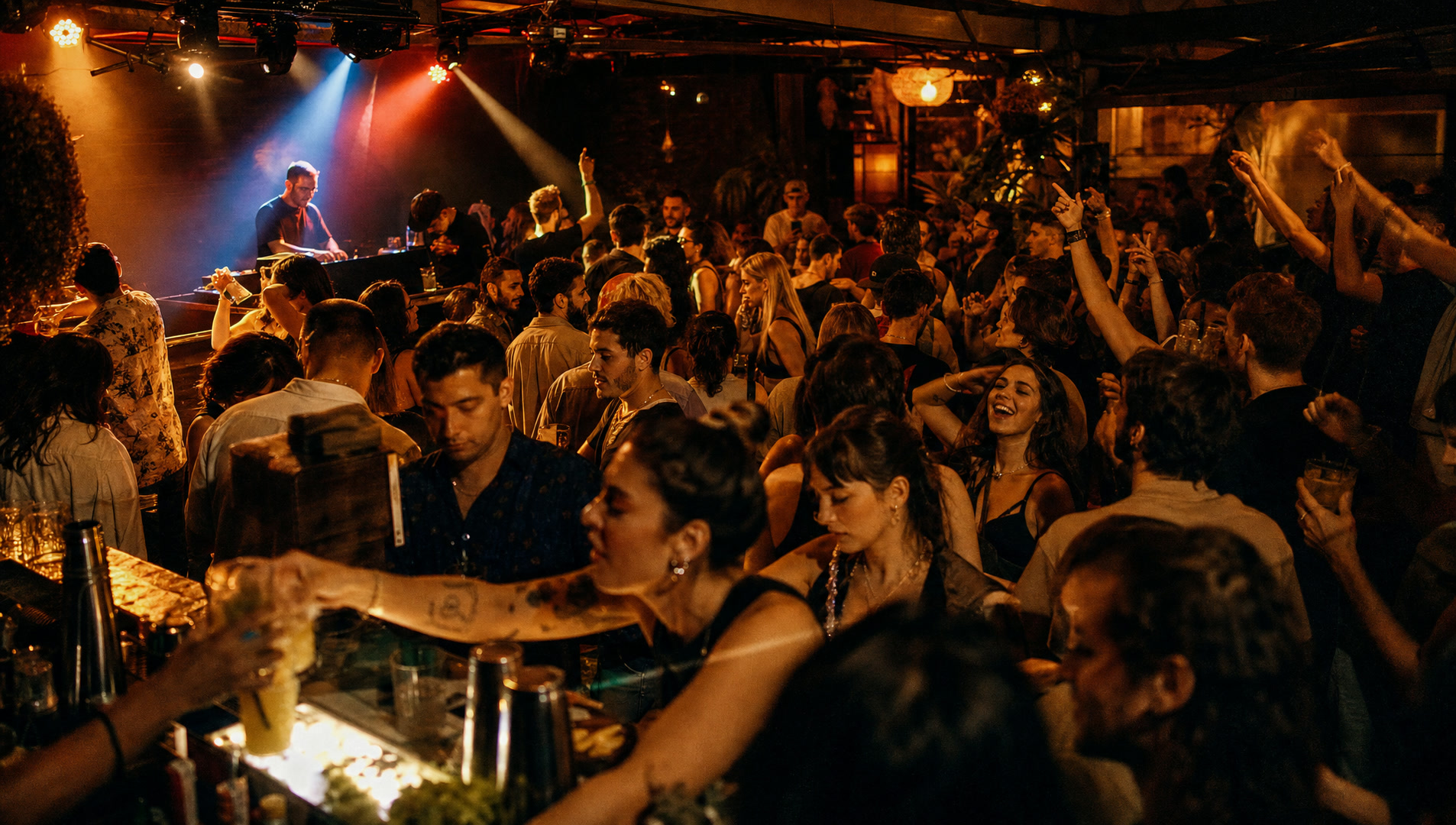 A crowd dancing in front of a DJ booth