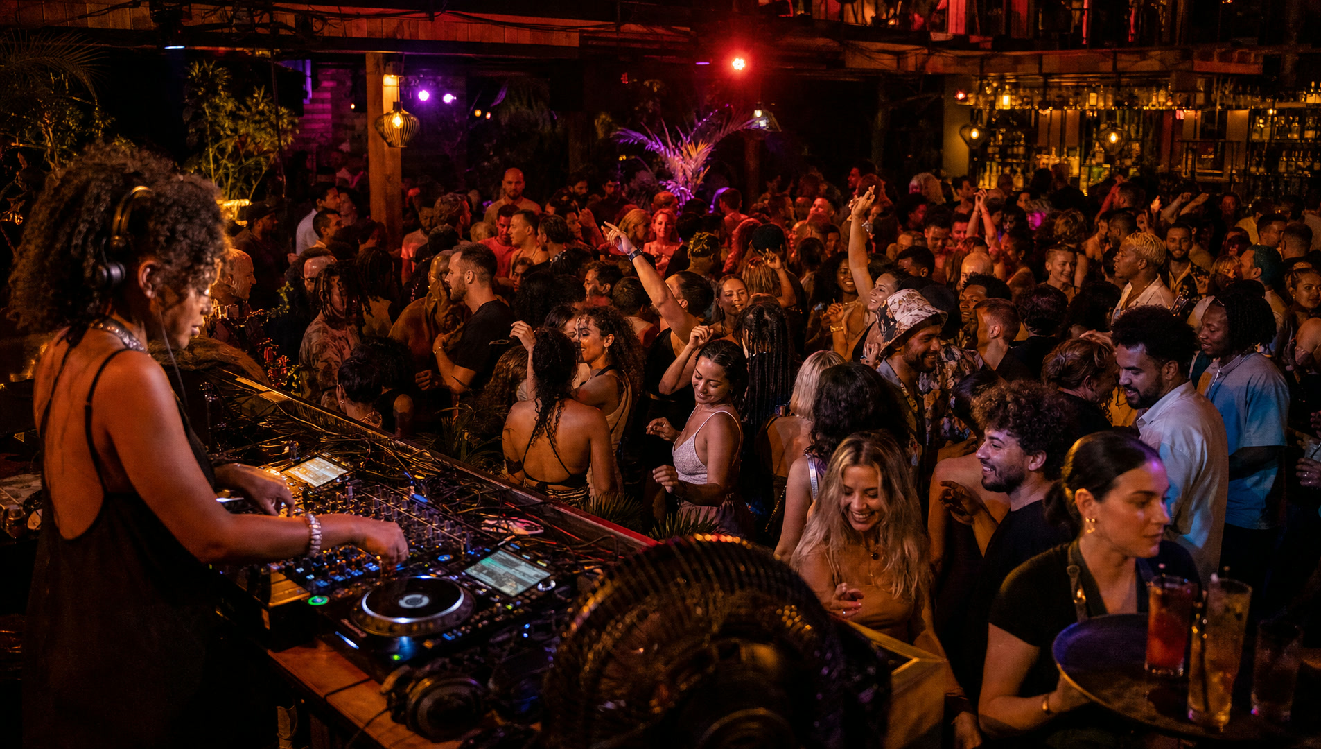 A crowd dancing in front of a DJ booth